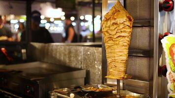Rotating doner kebab at a bustling market stall video