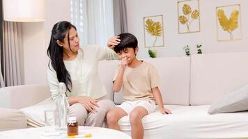 A mother checks her child's temperature and offers medicine in a cozy living room setting video
