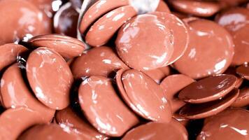 Spoon mixing shiny chocolate discs in motion video