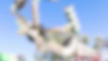 Blurred carnival ride spins rapidly against a clear blue sky, creating a dynamic and energetic atmosphere video