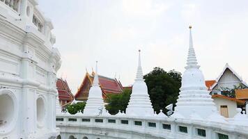 A tranquil showcasing the stunning architecture of Wat Prayurawongsawat in Bangkok, with white pagodas and lush greenery video