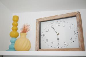 Bright home decor featuring a clock and vases on a shelf photo