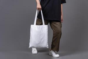 Female Walking While Holding Blank Canvas Tote Bag, Eco-Friendly Reusable Fabric with Handle, Close-Up Mockup, No Plastic and Environmental Concept photo