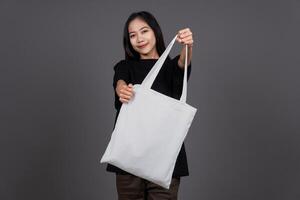 Female Holding Blank Canvas Tote Bag, Eco-Friendly Reusable Fabric with Handle, Close-Up Mockup, No Plastic and Environmental Concept photo