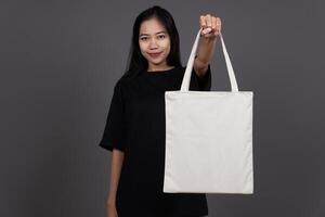 Front View of Woman Holding Blank Canvas Tote Bag, Eco-Friendly Reusable Fabric with Handle, Close-Up Mockup, No Plastic and Environmental Concept And Presenting photo