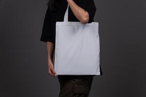 Front View of Woman Holding White Canvas Tote Bag, Eco-Friendly Reusable Fabric with Handle, Close-Up Mockup, No Plastic and Environmental Concept photo