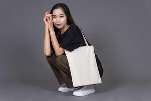 Woman Sitting on Floor Holding Blank Canvas Tote Bag, Eco-Friendly Reusable Fabric with Handle, Close-Up Mockup, No Plastic and Environmental Concept Isolated photo