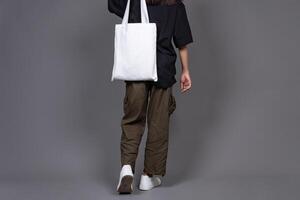 Female Walking While Holding Blank Canvas Tote Bag, Eco-Friendly Reusable Fabric with Handle, Close-Up Mockup, No Plastic and Environmental Concept Isolated photo