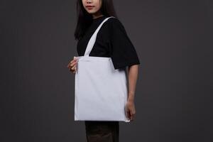 Side View of Female Holding Blank Canvas Tote Bag, Eco-Friendly Reusable Fabric with Handle, Close-Up Mockup, No Plastic and Environmental Concept photo