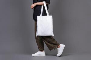 Female Walking While Holding Blank Canvas Tote Bag, Eco-Friendly Reusable Fabric with Handle, Close-Up Mockup, No Plastic and Environmental Concept Isolated Background photo