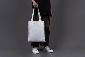 Front View of Woman Holding Blank Canvas Tote Bag, Eco-Friendly Reusable Fabric with Handle, Close-Up Mockup, No Plastic and Environmental Concept Background photo