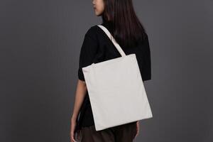 Back View of Female Holding Blank Canvas Tote Bag, Eco-Friendly Reusable Fabric with Handle, Close-Up Mockup, No Plastic and Environmental Concept Background photo
