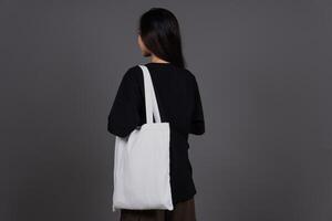 Back View of Female Holding Blank Canvas Tote Bag, Eco-Friendly Reusable Fabric with Handle, Close-Up Mockup, No Plastic and Environmental Concept Isolated Background photo