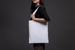 Side View of Female Holding Blank Canvas Tote Bag, Eco-Friendly Reusable Fabric with Handle, Close-Up Mockup, No Plastic and Environmental Concept Background photo