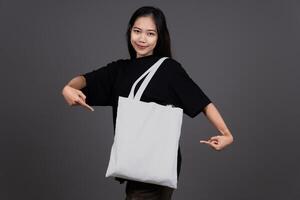 Front View of Woman Holding Blank Canvas Tote Bag, Eco-Friendly Reusable Fabric with Handle, Close-Up Mockup, No Plastic and Environmental photo