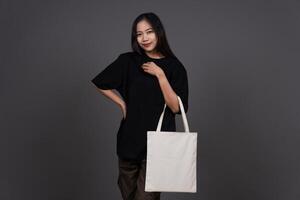 Front View of Beauty Woman Holding Blank Canvas Tote Bag, Eco-Friendly Reusable Fabric with Handle, Close-Up Mockup, No Plastic and Environmental Concept photo
