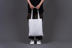 Front View of Woman Holding Blank Canvas Tote Bag, Eco-Friendly Reusable Fabric with Handle, Close-Up Mockup, No Plastic and Environmental Concept photo