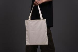 Side View of Woman Holding Blank Canvas Tote Bag, Eco-Friendly Reusable Fabric with Handle, Close-Up Mockup, No Plastic and Environmental Concept photo