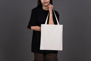 Front View of Woman Holding Blank Canvas Tote Bag, Eco-Friendly Reusable Fabric with Handle, Close-Up Mockup, No Plastic Concept photo