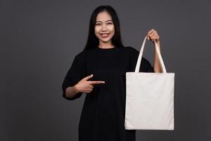 Front View of Woman Holding Blank Canvas Tote Bag, Eco-Friendly Reusable Fabric with Handle, Close-Up Mockup, No Plastic and Environmental Smiling Concept photo