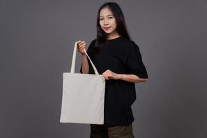 Woman Holding Blank Canvas Tote Bag, Eco-Friendly Reusable Fabric with Handle, Close-Up Mockup, No Plastic and Environmental Concept photo
