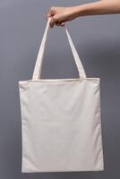 Female Hand Holding White Canvas Tote Bag, Eco-Friendly Reusable Fabric with Handle, Close-Up Mockup, No Plastic and Environmental Concept photo