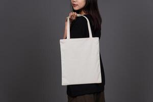 Back View of Female Holding Blank Canvas Tote Bag, Eco-Friendly Reusable Fabric with Handle, Close-Up Mockup, No Plastic and Environmental Concept photo