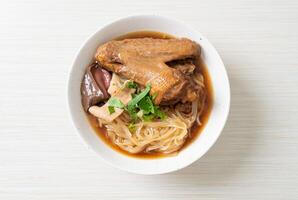Braised duck noodles with brown soup on wooden background. photo