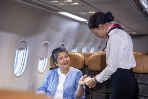 Flight attendant is welcoming and checking senior woman passenger boarding pass and show her seat for airplane flight and airline transportation service photo