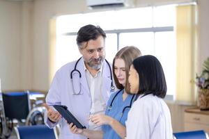 Team of diversity doctor and nurse are discussing and brainstorming over patient medical record after diagnosis for precise care plan with experienced senior specialist photo