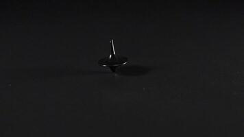 A spinning top rotating on a dark surface video