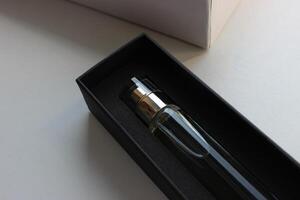 Black gift box with perfume near a white cardboard case on a white surface photo
