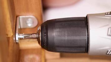 A power drill secures screws into wooden furniture, showcasing efficient assembly in a well-lit environment video