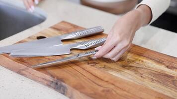 A person arranges knives on a wooden cutting board in a well-lit kitchen setting video