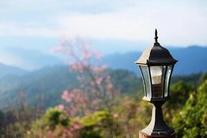 Beautiful classic and vintage black iron street lamp on mountain and forest view with blue sky. Copy space photo