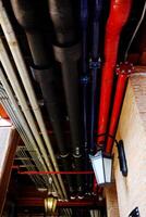 Detail of industrial pipes with ventilation systems and ducts conduits arrangement in mechanical system on ceiling of basement photo