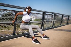 Urban fitness scene showing fit African female performing a reverse push ups, headphones on, immersed in her healthy routine. photo