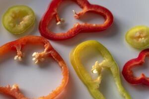 Pepper rings on white plate. Red, orange and green slices. Closeup with selective focus. photo