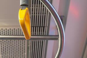 Hanging handle and handrails in public transport. Yellow handle. Circle metal handrail. Selective focus. photo