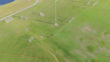 Aerial drone footage captures a soccer field with robotic lines on a sunny day, showcasing a unique sports technology video