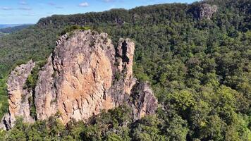 Drone footage captures the majestic Nimbin Rocks surrounded by lush greenery under clear blue skies in New South Wales video