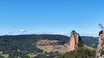 Panoramic view of Nimbin Rocks under clear blue skies, showcasing natural rock formations and lush greenery video