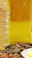 Close-up of sunflower and almond seeds with bottles of oil on a wooden background, highlighting textures and colors video