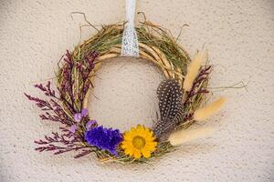 Handmade wreath crafted from dried flowers and herbs showcasing vibrant sunflowers, lavender, and delicate feathers, perfect for unique home decoration photo