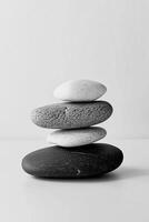 Monochrome image of four smooth stones stacked on top of each other in a balanced tower form photo