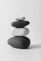 Stack of four smooth stones in grayscale on a white background in a vertical orientation photo