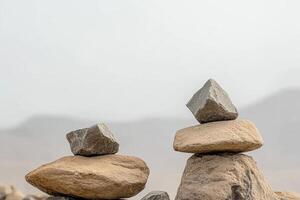A zen rock balancing art installation featuring stacked stones against a blurred background photo
