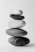 A harmonious stack of five smooth stones in varying shades of gray and white on a white backdrop photo