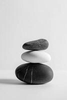 A monochromatic image displaying a stack of three smooth stones in a balanced arrangement photo