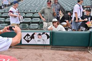 A security guard takes a photo of a fan near the recently installed memorial of the late Chicago White Sox pitcher Bobby Jenks prior to a game against the Cleveland Guardians at Rate Field. editorial_image